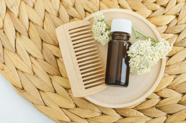 Small bottle with essential yarrow oil and yarrow flowers. Aromatherapy, homemade beauty treatment and herbal medicine ingredients.