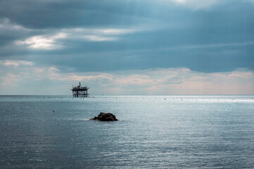 An abandoned offshore platform in the rays of the sun shining through thick clouds