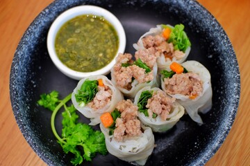 Close up view of Asian appetiser, Vietnamese spring rolls served with dipping sauce on dinning table