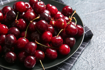 Obraz na płótnie Canvas Plate with sweet cherries on dark table