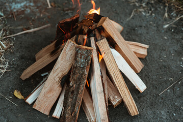 A bright flame of fire over a campfire. Wooden wood stacked in a pyramid is burning. The flame of fire close-up