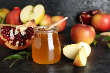 Jar of honey, pomegranate and apples for Rosh Hashanah celebration (Jewish New Year) on black table