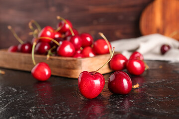 Wooden board sweet cherries on black table