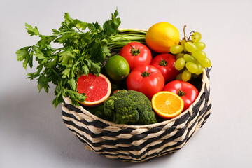 Wicker bowl with different fresh fruits and vegetables on white background