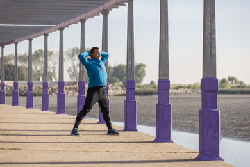 Latino runner stretching in a pergola in a public park.
