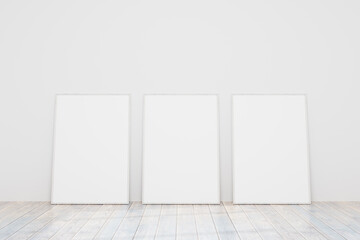 Three empty wooden frames for a photo or picture on the floor near a white wall. Models of...