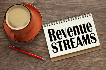 REVENUE STREAMS open notebook with text near orange mug