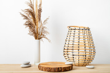 Minimal natural wood home decor with pine wood disc pedestal with bark, dry reed in vase and round...