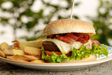 The yummy burger with homemade craft french fries on the blue plate filmed outside 