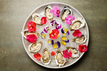 The top view of the delicious appetizer with raw mussels on the ice decorated with flowers