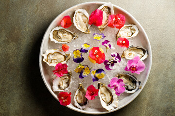 The top view of the delicious appetizer with raw mussels on the ice decorated with flowers