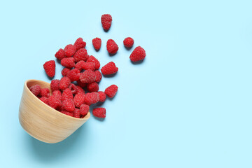 Bowl with fresh raspberries on blue background