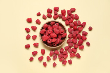 Bowl with fresh raspberries on yellow background