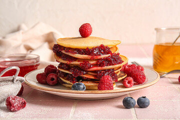 Plate of tasty pancakes with raspberries and blueberries on table