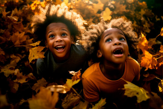 black kids playing in autumn leaves on a sunny day