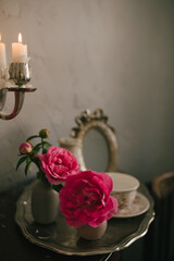 Still life with many different garden roses on a vintage table on grey background.