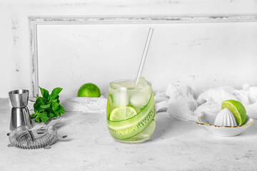 Glass of mojito with cucumber on grunge white background