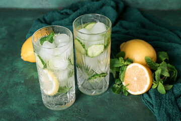Glasses of mojito with cucumber on grunge green table
