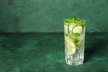 Glass of mojito with cucumber on grunge green table