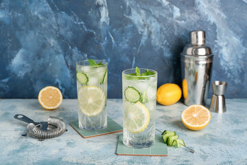 Glasses of mojito with cucumber on grunge light blue table