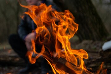 A fire burns in a campfire with a red fire in the background.