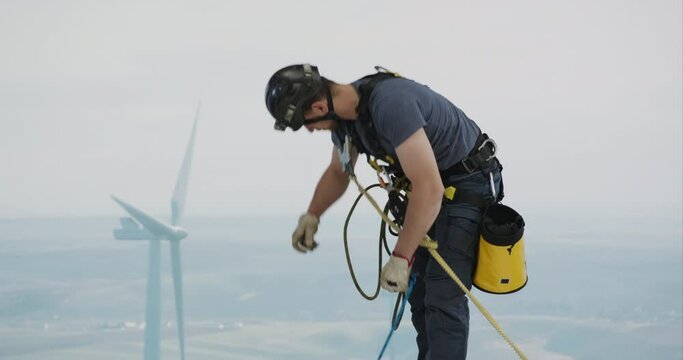 Engineer performing repairing and maintenance works on top of wind turbine nacelle house. Portrait of skilled professional worker working at high altitude 