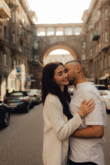 The couple walks around Kyiv. Old city. Love story. Walk around the city. A woman in a white suit. Guy in a t-shirt and jeans. Love and hugs. To cross the road. No focus blurred and noise effect