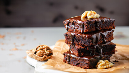 Chocolate spongy brownie cakes with walnuts and melted chocolate topping on a stack