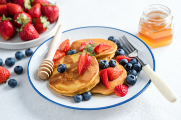 Delicious gluten free corn pancakes with sweet summer berry fruits and honey, closeup view