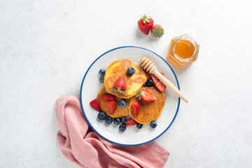 Healthy gluten free corn pancakes with berries and honey on a grey concrete table background, table...