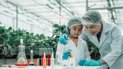 A scientist father guides his daughter in farming using a pH meter. Measuring acid-base levels in water to ensure right conditions for strawberry growth. Combining expertise with technological tools.