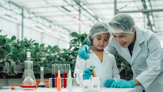A scientist father guides his daughter in farming using a pH meter. Measuring acid-base levels in water to ensure right conditions for strawberry growth. Combining expertise with technological tools.