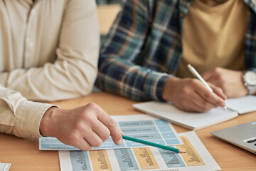 Close-up of teacher pointing at cards on table and explaining new material to foreign student