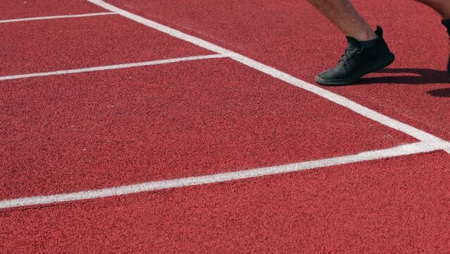 Man starts for a run. Side view of an athlete starting a sprint on a treadmill. The runner uses the starting block to start his run on the race track.