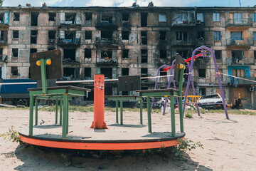 An empty children's playground next to a residential building destroyed by rocket fire. War in...