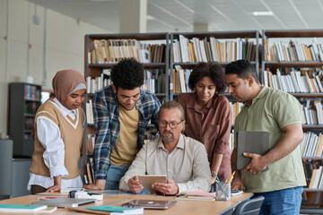 Teacher having lesson with migrant students, they watching presentation on digital tablet during lesson