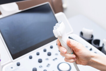 Woman doctor's hand aholding a medical gel to ultrasonic sensor of ultrasound machine in the clinic