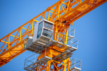 Load-lifting crane on a construction site against the blue sky. A group of lifting platforms for construction and handling operations. Close-up of a basket for transporting people