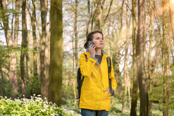 Woman using her mobile phone in the woods. Lost or calling for assistance.