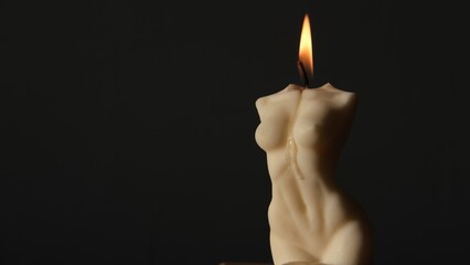 Burning soy or wax candle in shape of aesthetic female body on gray background. Concept of femininity and beauty.
