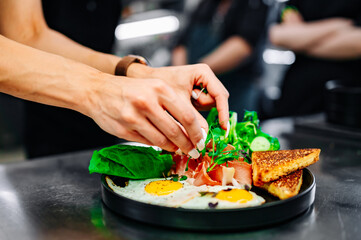 woman chef hand cooking fried eggs with ham, salad and hummus