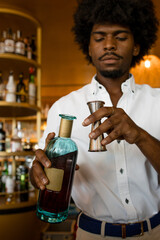 vertical photo of a latin bartender with curly hair with a bottle of alcohol