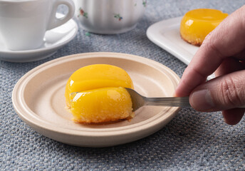 Hand holding fork cutting quindim, traditional egg and coconut brazilian dessert