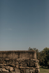 Old masonry wall. Stone wall style walls of a huge farm with old house, trees, blue flowers and grazing horses.