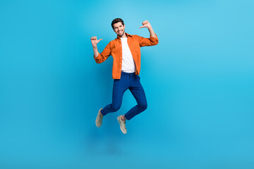 Fototapeta na wymiar Full length portrait of crazy carefree active man jumping point fingers self himself isolated on blue color background