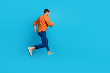 Fototapeta na wymiar Full size profile rear portrait of energetic crazy young man jumping running empty space advert isolated on blue color background