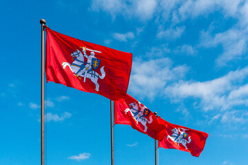 Historical Lithuanian flags waving in the wind against blue sky