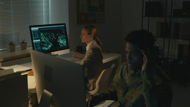 Medium full shot of three multiracial military officers having emergency situation in surveillance hub at night