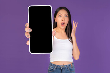 Beautiful Asian brunette woman cute girl in white tank top ,Excited surprised girl showing big smart phone with blank screen , black screen isolated purple background , Mock Up Image