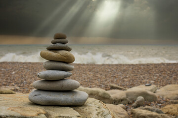 Pyramid of stones in the sand at the beach and waves